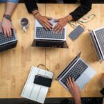 four people working at laptops around a center table; website maintenance; new southern solutions