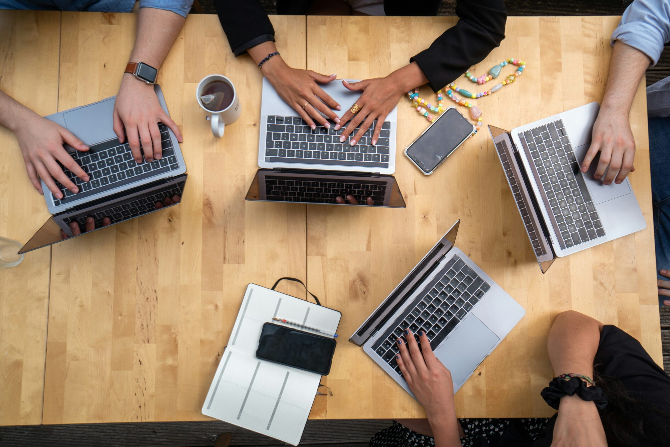 four people working at laptops around a center table; website maintenance; new southern solutions